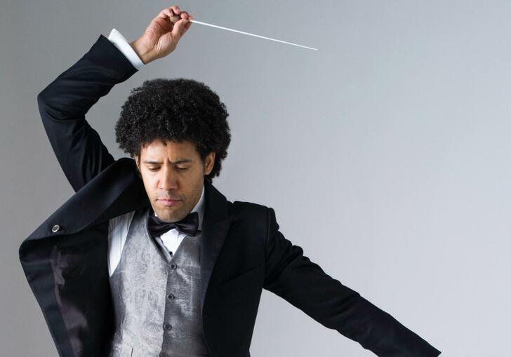 Rafael Payare striking a pose with his baton held above his head