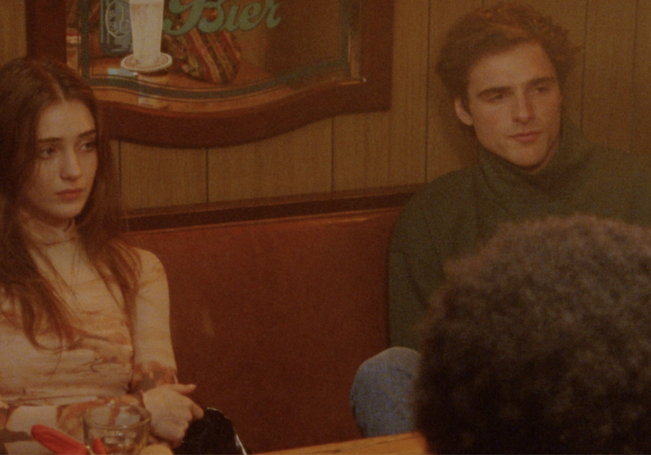 Two teenagers sit in a diner booth, looking dazed.