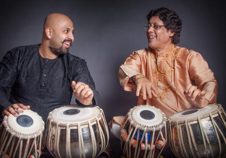 Anindo and Anubratta Chatterjee playing the tabla, smiling at each other