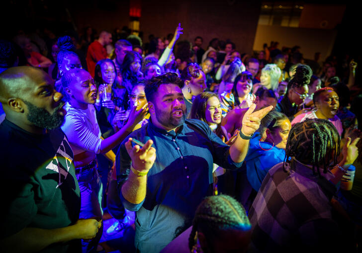 A group of people move on the dance floor to music.