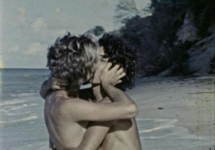 Two women embrace on a tropical beach.