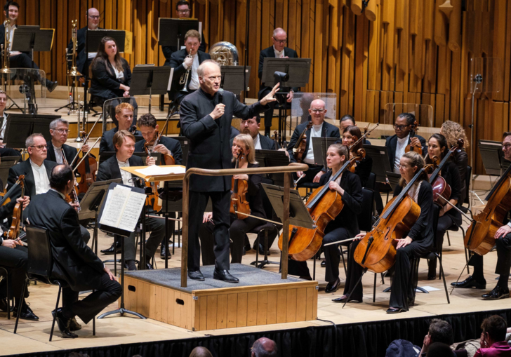 Conductor Gianandrea Noseda holds a microphone and presents his pre-concert Half Six Fix talk