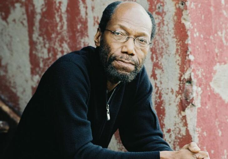 Charles Tolliver looks to camera, sitting on stairs