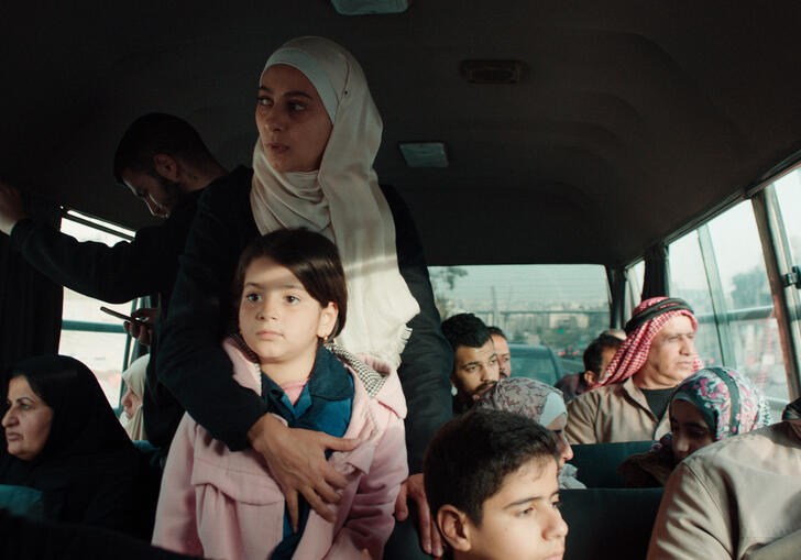 A woman holds a young child on a busy bus.