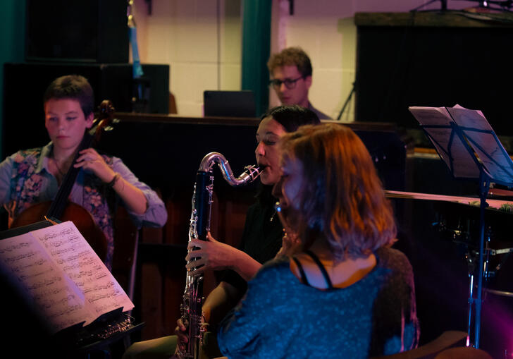 A cellist, bass clarinettist, flautist and pianist sitting playing their instruments