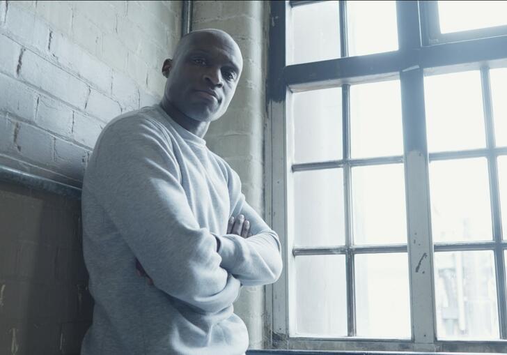 Image of man leaning against wall by a window