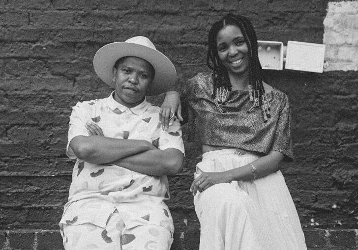 Siya and Thandi leaning against a brick wall