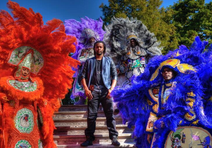 Bo Ellis stands surrounded Mardi Gras performers