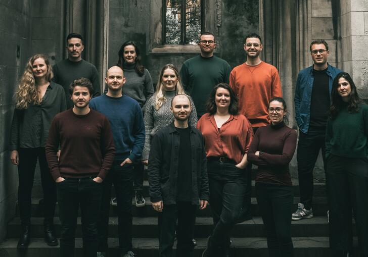 Sansara Choir standing on the steps of an old, abandoned church