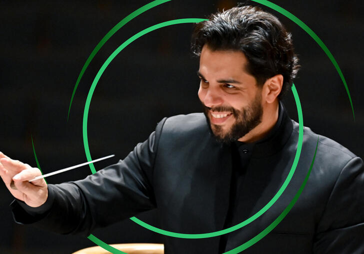 Domingo Hindoyan conducting, with green circular swirls around him