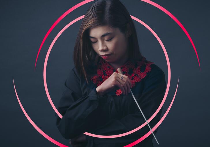 Elim Chan holding her baton, with pink circular swirls around her