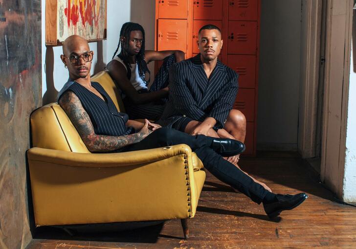 Davóne Tines, Khari Lucas and John Bitoy sitting on a yellow sofa