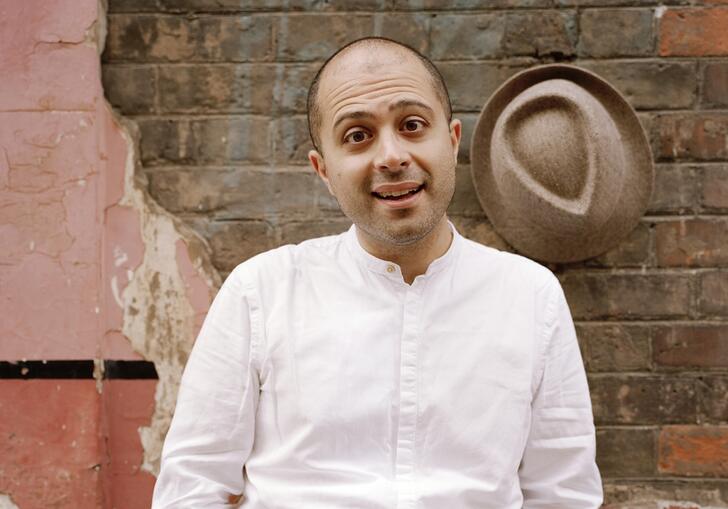 Mahan Esfahani standing in front of a brick wall