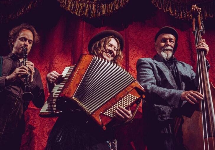 Whsikey Moonface energetically play their instruments against a red velvet curtain