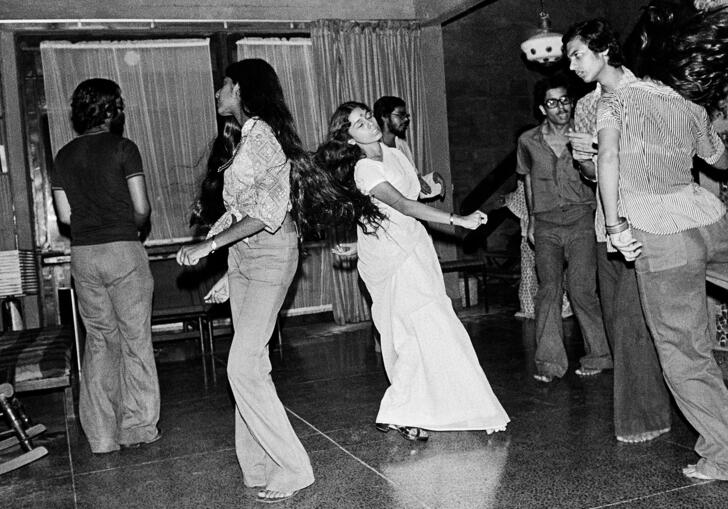 A black and white photo by Pablo Bartholomew, showing a group of people dancing at a party in New Delhi in 1975