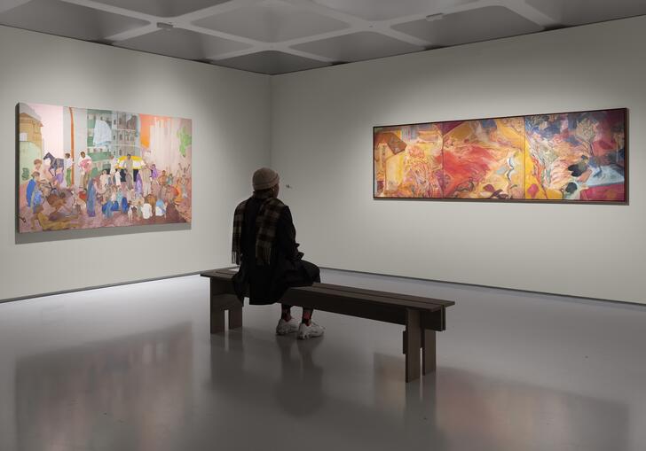 a person sits on a bench in front of two paintings
