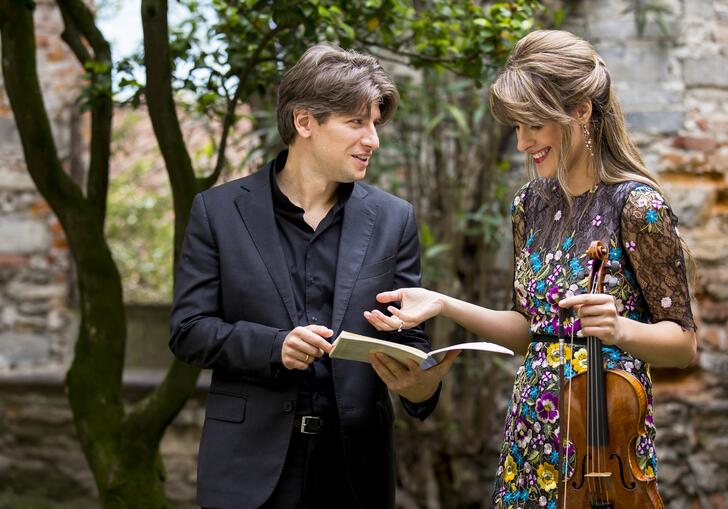 Conductor Daniele Rustinoi and violinist Francesca Dego chatting in a park