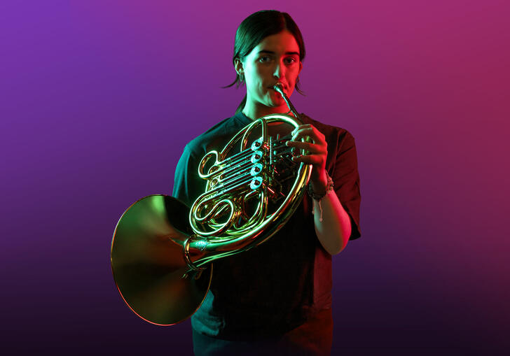 Horn player on a purple background