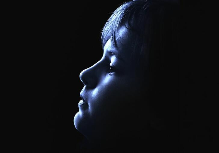 Image of young boy looking up with face in shadow