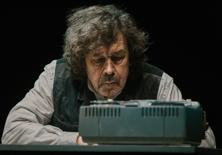 Actor Stephen Rea sits in front of a tape machine.