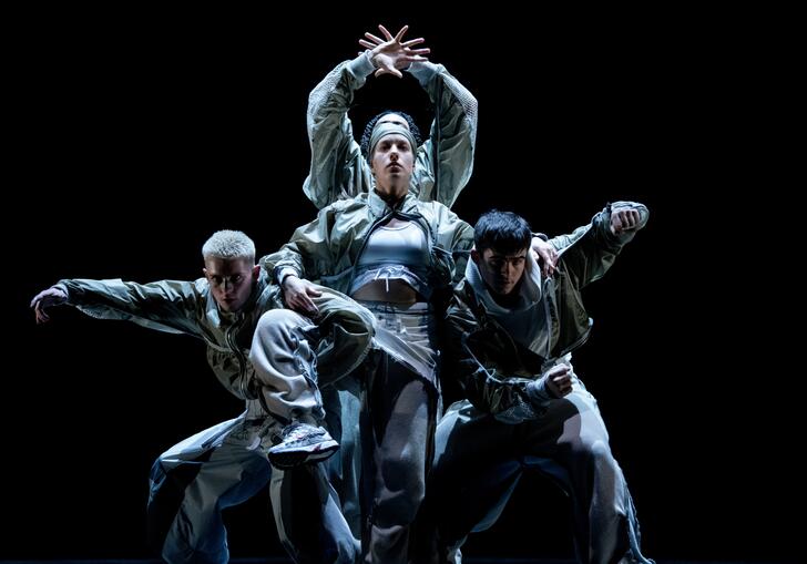 A group of dancers move around each other. They move at different levels creating one moving entity. 