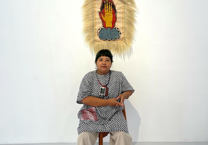 The artist sits in front of a portrait