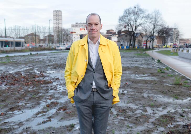 Kristiaan Borret standing on a waterlogged building site, wearing a bright yellow jacket.