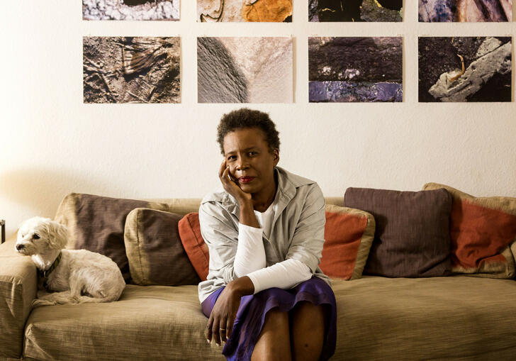 Claudia Rankine sitting on a sofa, resting her head in her hand.