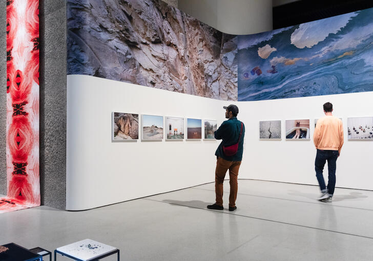 two people stand in the gallery space, looking at the ReSisters exhibition 