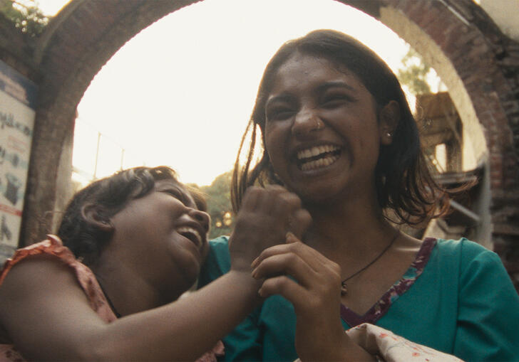 Two women laugh and hold hands.