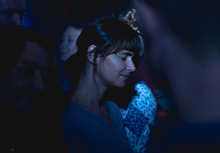 Joana Santos stands in a crowd, covered in blue light
