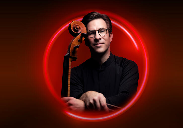 An image of Guy Johnston surrounded by a red circle against a red backdrop