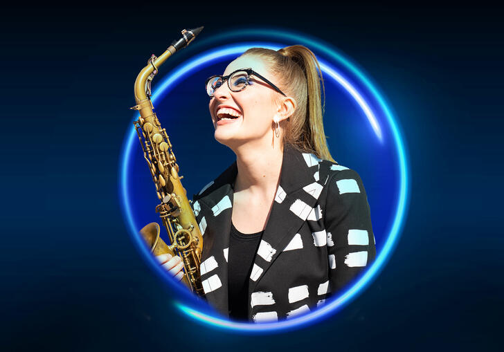 Jess Gillam holding a saxophone against a blue backdrop