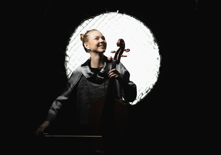 Valerie Fritz holding a cello in front of a stage light