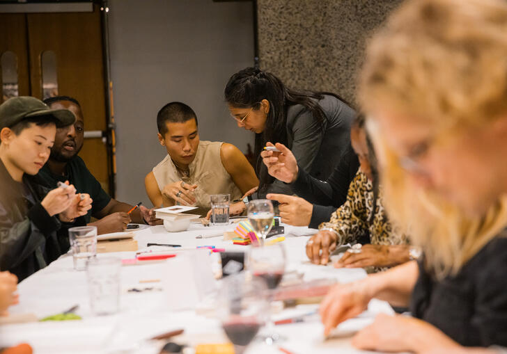 Image of multiple people sat around a long desk with a white cover making slime