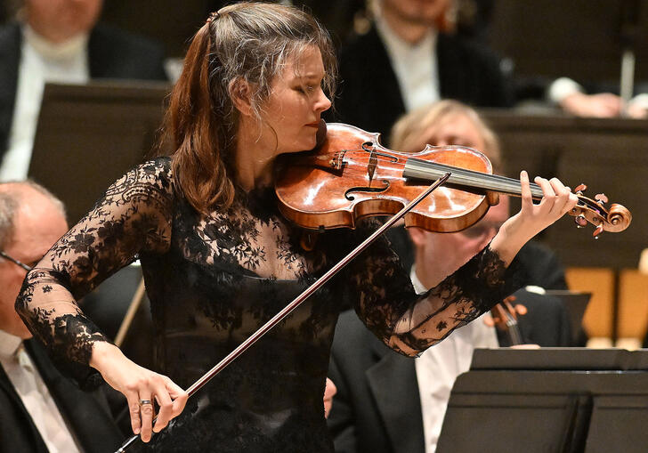 Janine Jansen on the Barbican stage, in front of the orchestra, playing the violin