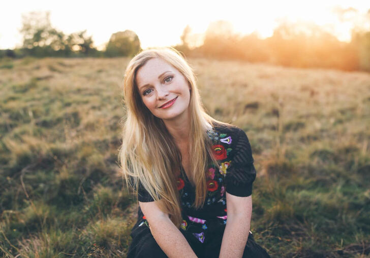 Soprano Lucy Crowe pictured in a field, with the sun setting in the background
