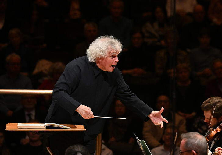Sir Simon Rattle conducting from the podium in the Barbican concert hall