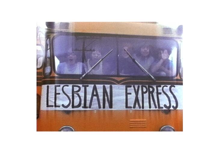 A still from Superdyke, showing the front of a bus with a group of women inside. On the front of the bus is a large banner saying Lesbian Express.