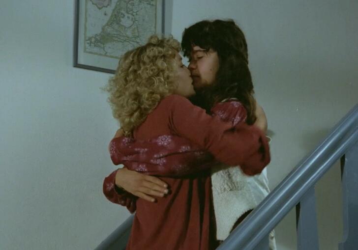 Two women embracing and kissing on a staircase
