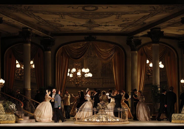 A scene from Arabella showing a group of men and women in 19th-century formal wear, standing in a grand ballroom