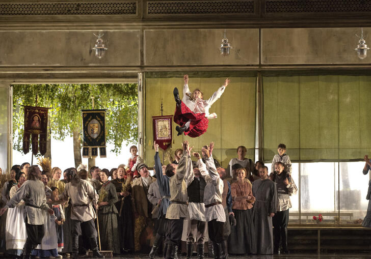 A woman in a red skirt is thrown into the air in this stage production of Eugene Onegin
