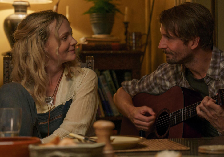 Carey Mulligan smiles at a man playing a guitar