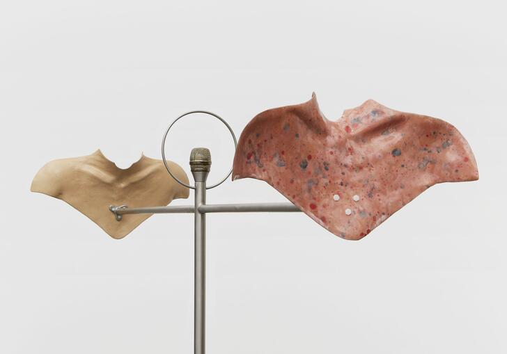 a sculpture shows ceramic moulds of human body parts lifted onto metal infrastructure