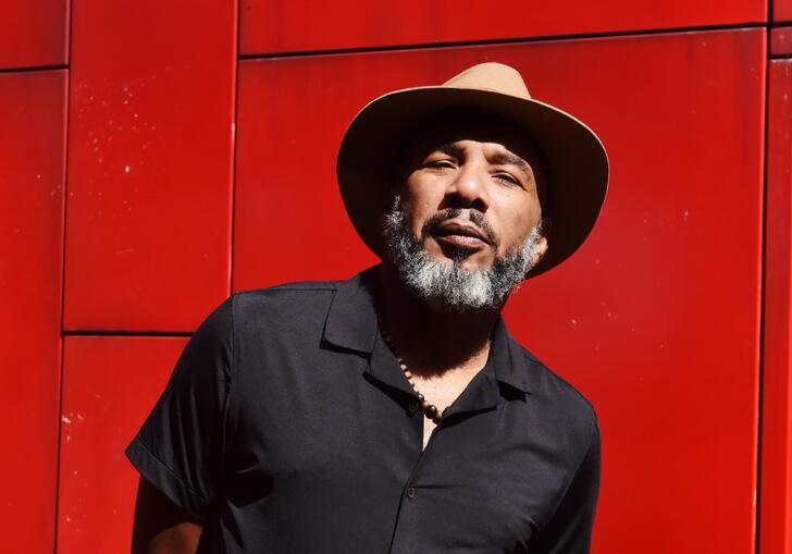 Image of Anthony Joseph in a hat against a red background
