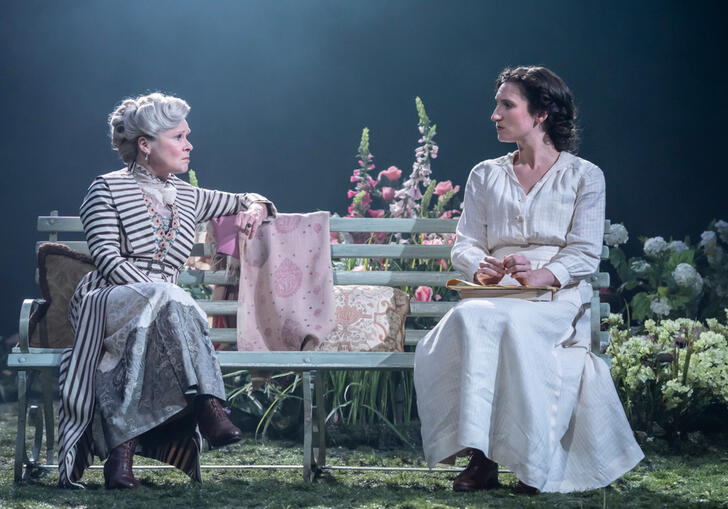 Two women sit on a bench looking at each other