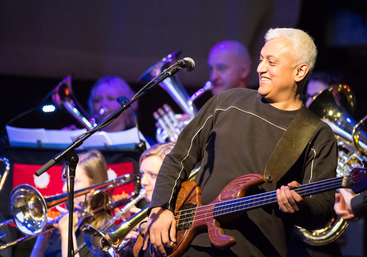 Shri Sriram playing a string instrument in front of a classical brass band