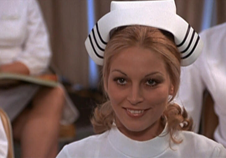 A nurse looks straight ahead, smiling. 