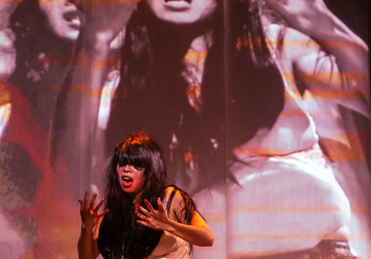 A person on their knees looking at their hands and screaming