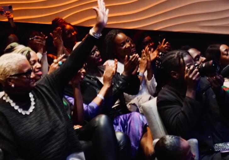 An audience of people actively engaging and participating in an event by raising their hands